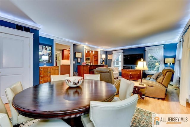 dining room featuring light wood-type flooring and crown molding