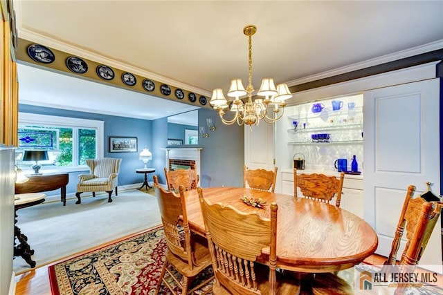 carpeted dining room with a fireplace, an inviting chandelier, and crown molding