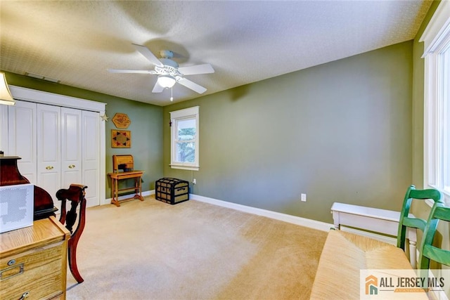 carpeted office space with a textured ceiling and ceiling fan