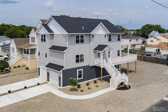 exterior space with fence, driveway, a shingled roof, stairs, and a residential view