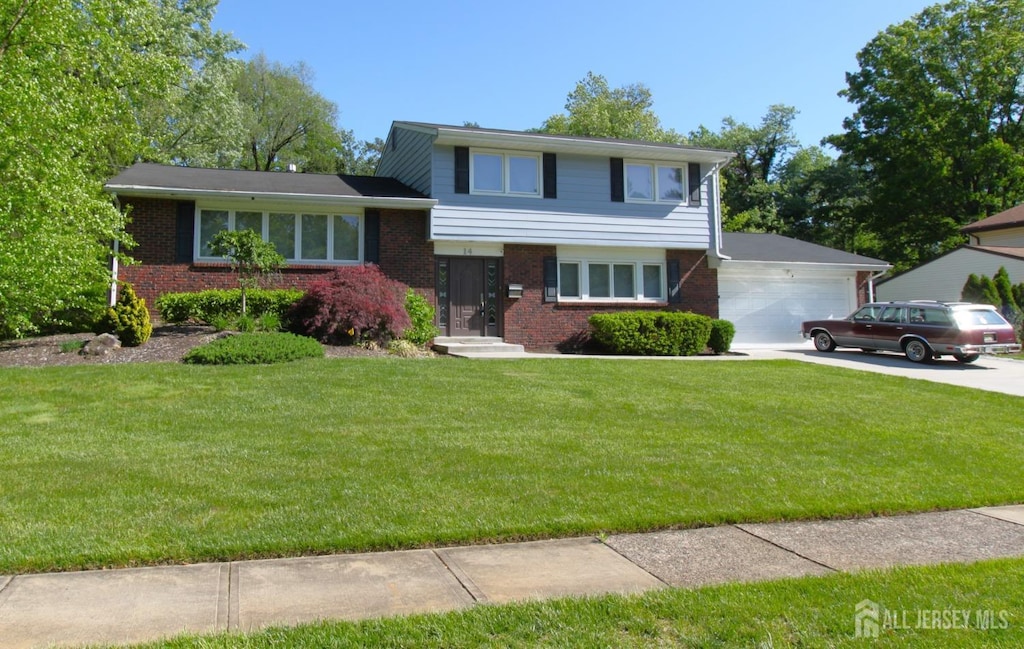 tri-level home featuring brick siding, a garage, a front lawn, and driveway