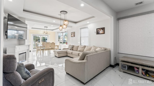 living room with recessed lighting, visible vents, marble finish floor, a raised ceiling, and a glass covered fireplace