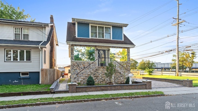 view of front facade with a shingled roof and fence