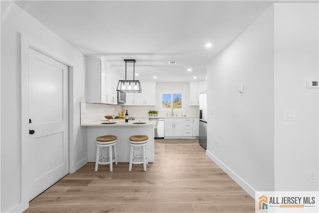 737 Prospect Rd Unit 737A, Monroe, NJ 08831 - kitchen featuring dishwasher, a peninsula, decorative backsplash, light countertops, and white cabinetry