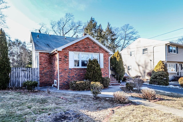 bungalow-style home featuring brick siding and fence