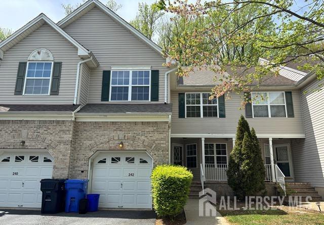 242 Hawthorne Rd, North Brunswick, NJ 08902 - view of front of home featuring an attached garage, brick siding, and a porch