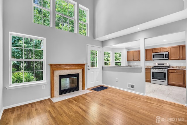 242 Hawthorne Rd, North Brunswick, NJ 08902 - unfurnished living room with light wood finished floors, a high end fireplace, a high ceiling, and recessed lighting