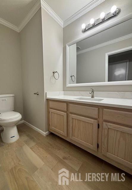 bathroom featuring vanity, ornamental molding, wood finished floors, and toilet