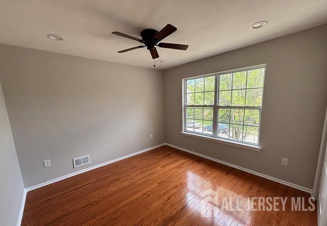 empty room with visible vents, wood finished floors, baseboards, ceiling fan, and recessed lighting