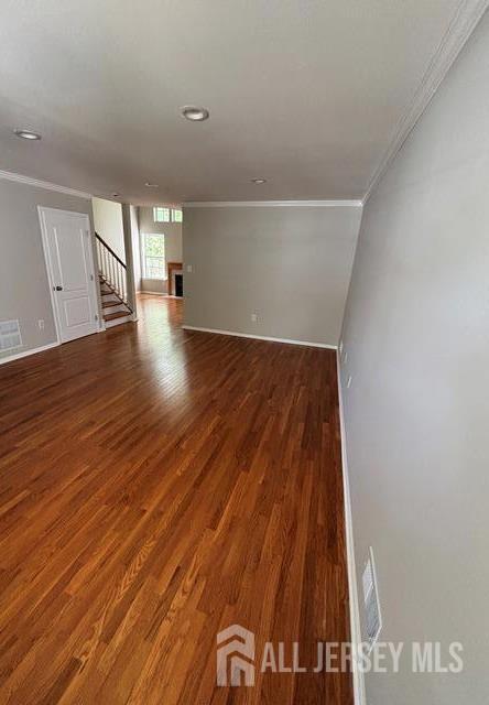 unfurnished room with crown molding, baseboards, stairs, and wood finished floors