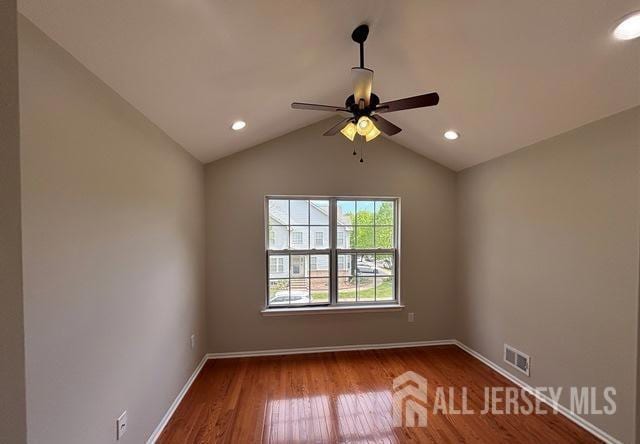 unfurnished room featuring visible vents, wood finished floors, baseboards, ceiling fan, and vaulted ceiling