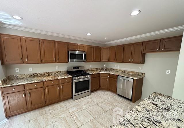 kitchen with crown molding, appliances with stainless steel finishes, and brown cabinetry