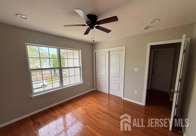 unfurnished bedroom with baseboards, a ceiling fan, a closet, and wood finished floors