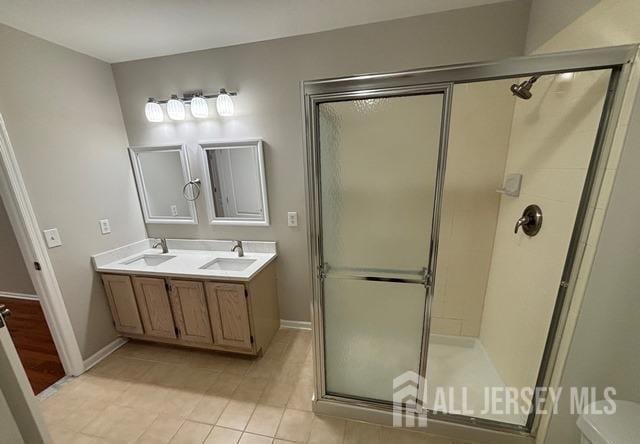 full bathroom with baseboards, a shower stall, a sink, and tile patterned flooring