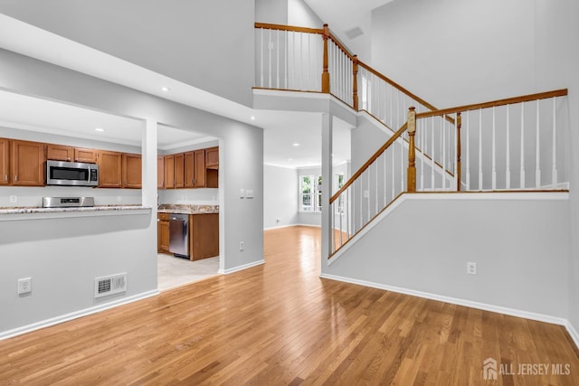 242 Hawthorne Rd, North Brunswick, NJ 08902 - unfurnished living room featuring light wood-type flooring, stairway, recessed lighting, and a towering ceiling