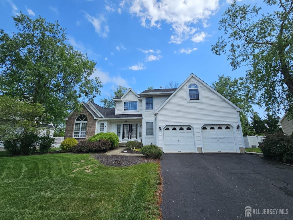traditional-style house featuring driveway, a garage, and a front yard