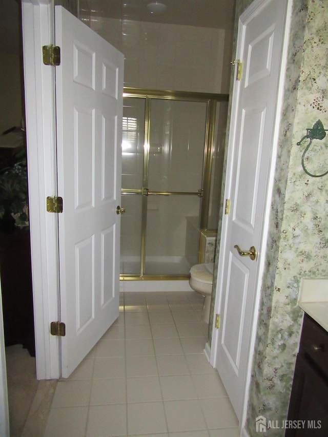 bathroom with an enclosed shower, vanity, tile patterned floors, and toilet