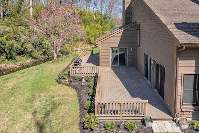 view of home's exterior featuring a wooden deck, a lawn, a chimney, and roof with shingles