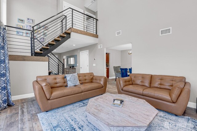 living area with wood finished floors, a high ceiling, baseboards, a chandelier, and stairs