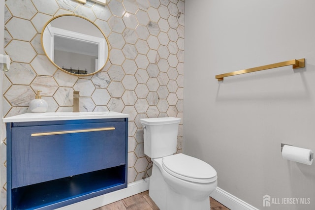 bathroom featuring tile walls, wood finished floors, vanity, and toilet