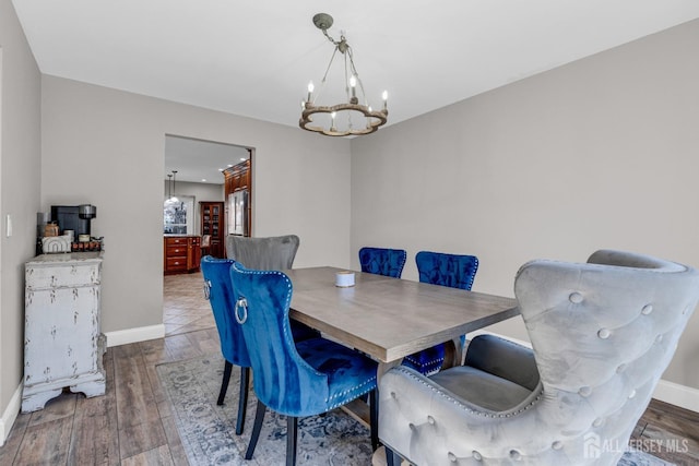 dining space featuring a chandelier, baseboards, and wood finished floors