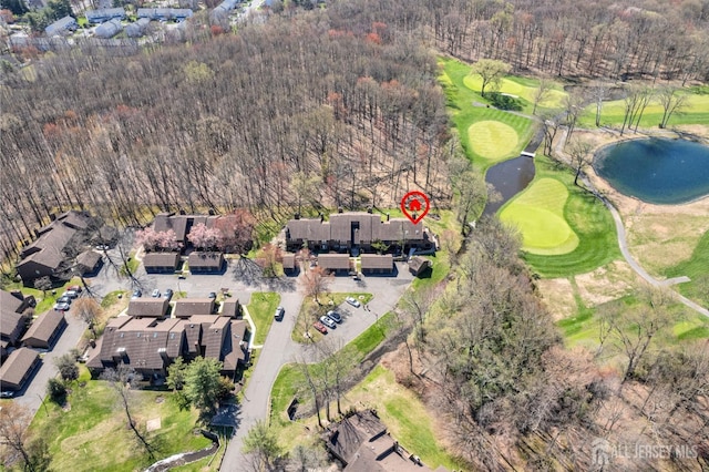 aerial view of property and surrounding area with a local golf course, a nearby body of water, and a heavily wooded area
