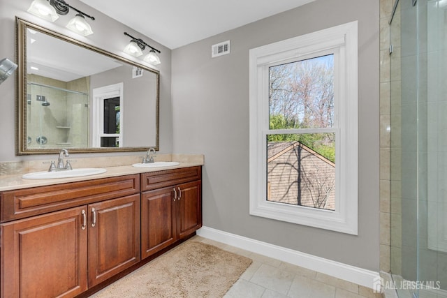 bathroom featuring tiled shower, baseboards, double vanity, and tile patterned floors