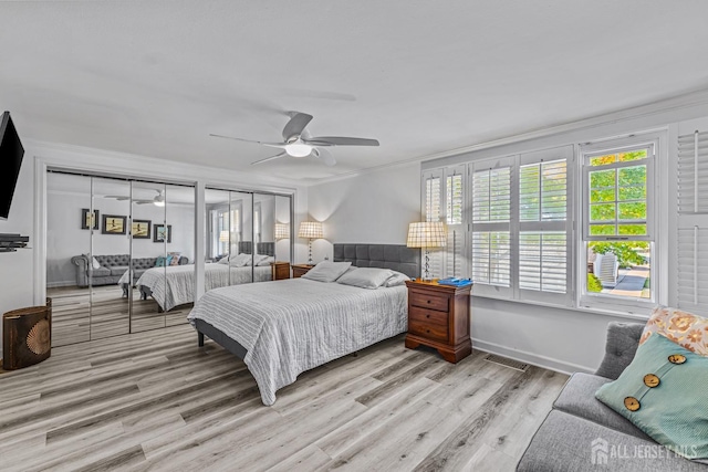 bedroom featuring ceiling fan, crown molding, light hardwood / wood-style floors, and two closets