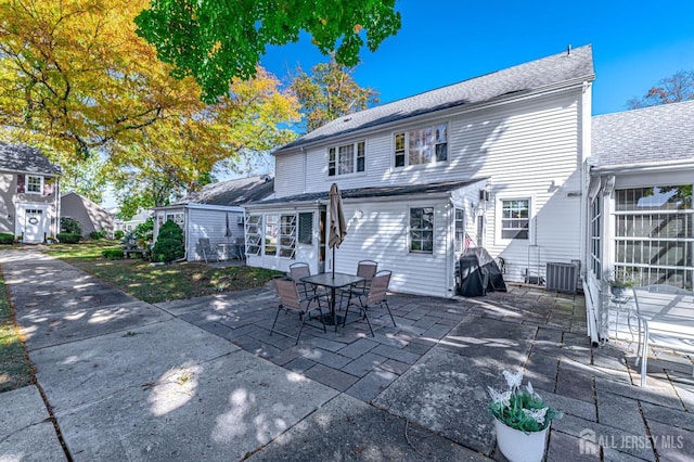 rear view of property with central air condition unit and a patio