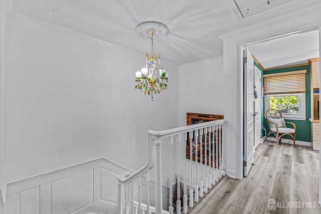 staircase featuring a chandelier, hardwood / wood-style floors, and ornamental molding