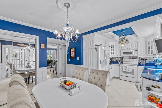 dining area with light tile patterned flooring, ornamental molding, sink, and an inviting chandelier