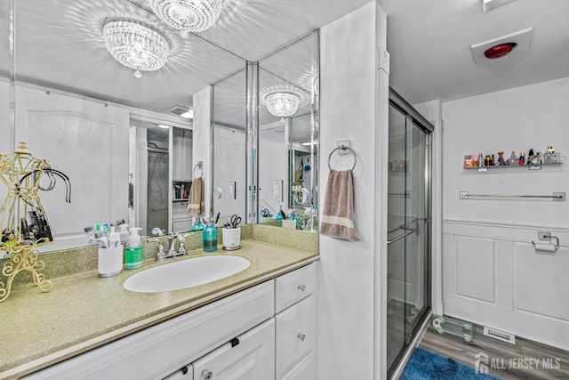 bathroom featuring hardwood / wood-style floors, vanity, a shower with shower door, and a chandelier