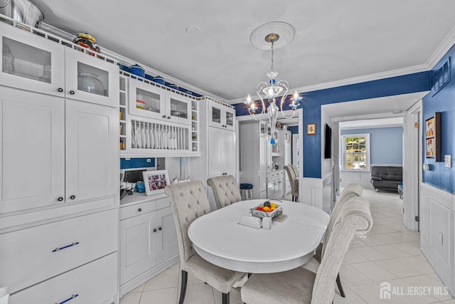 dining space with a notable chandelier, light tile patterned floors, and ornamental molding