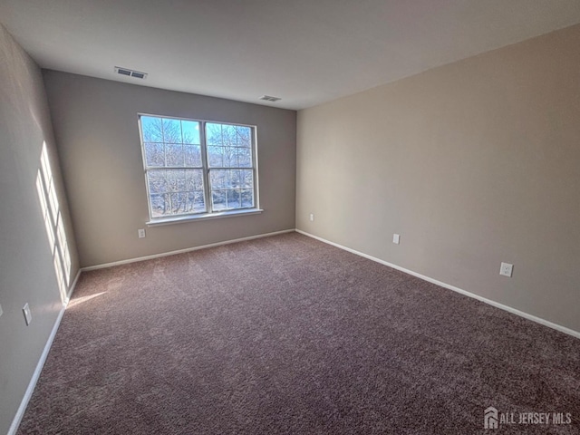 spare room featuring carpet flooring, visible vents, and baseboards