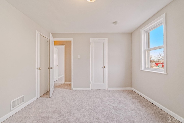 unfurnished bedroom with carpet, visible vents, and baseboards