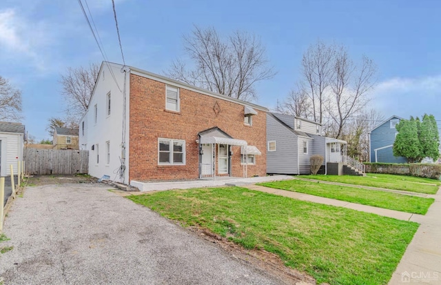 view of front of house with fence, a front lawn, and brick siding