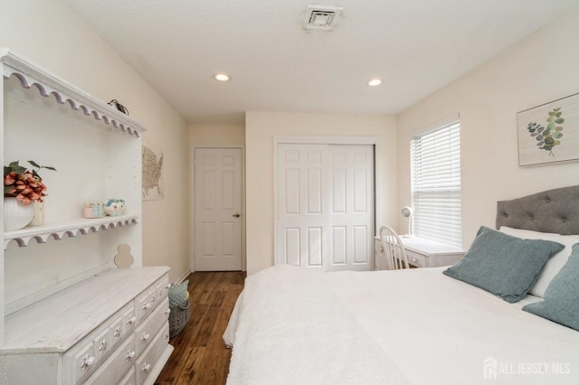 bedroom with a closet, recessed lighting, dark wood-style flooring, and visible vents