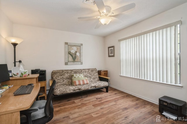 office space with baseboards, ceiling fan, wood finished floors, and a wealth of natural light