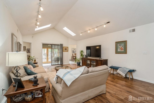 living area with vaulted ceiling with skylight, visible vents, rail lighting, wood finished floors, and baseboards