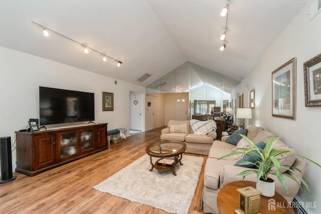 living area featuring light wood-style floors, track lighting, vaulted ceiling, and visible vents
