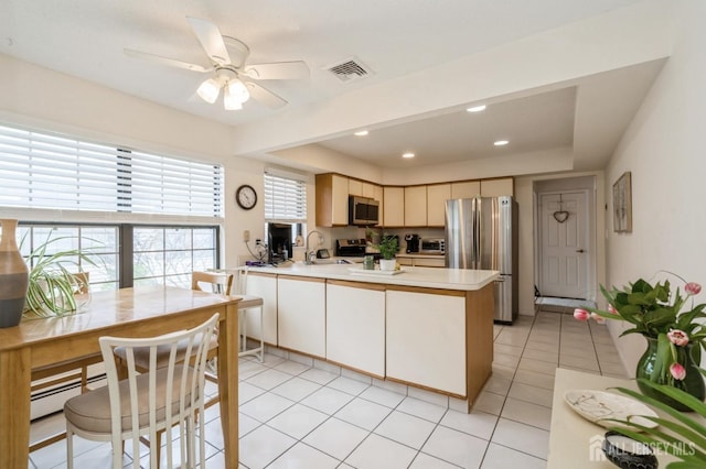 kitchen with visible vents, a peninsula, light countertops, a sink, and appliances with stainless steel finishes