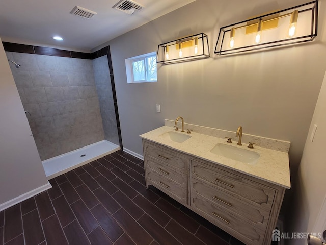 bathroom featuring tiled shower and vanity