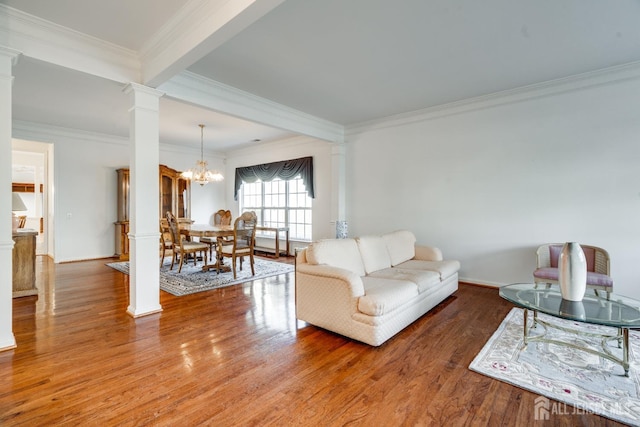 living room with decorative columns, wood-type flooring, ornamental molding, and an inviting chandelier