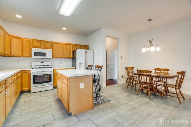 kitchen featuring a kitchen bar, a center island, white appliances, an inviting chandelier, and light countertops