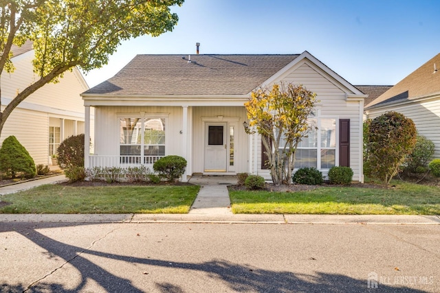 view of front of house featuring a porch, a shingled roof, and a front yard