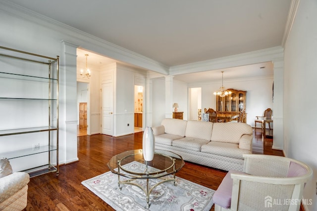 living room with dark wood-style floors, crown molding, decorative columns, and an inviting chandelier