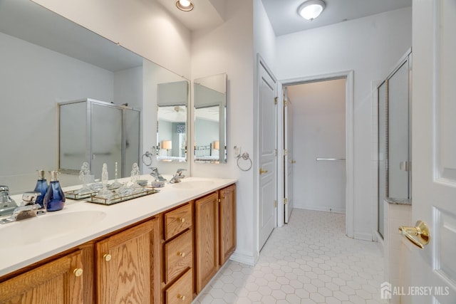 full bath with tile patterned flooring, double vanity, a stall shower, and a sink