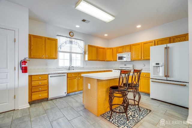 kitchen with visible vents, a center island, light countertops, recessed lighting, and white appliances