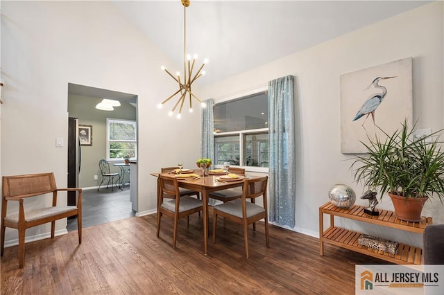 dining room with baseboards, a notable chandelier, wood finished floors, and vaulted ceiling