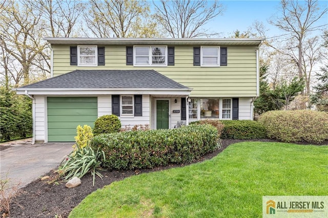 traditional-style house with an attached garage, a front yard, and aphalt driveway